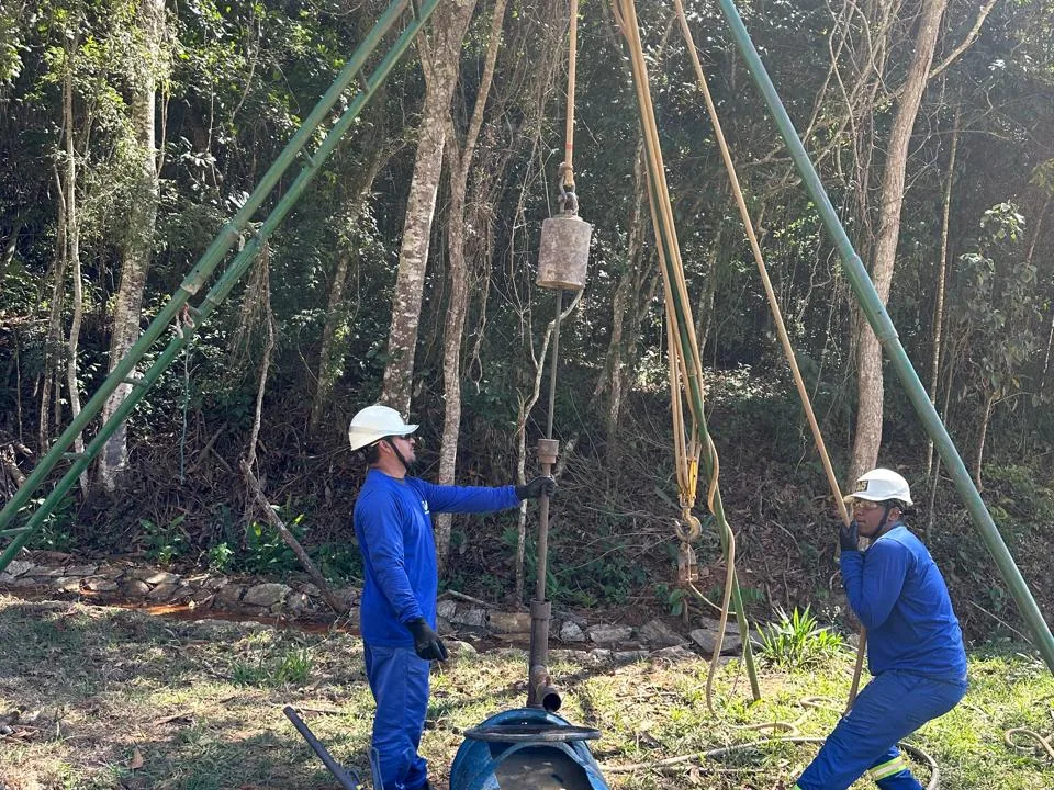 Equipe do Grupo CMG operando o tripé de sondagem SPT em terreno de mata